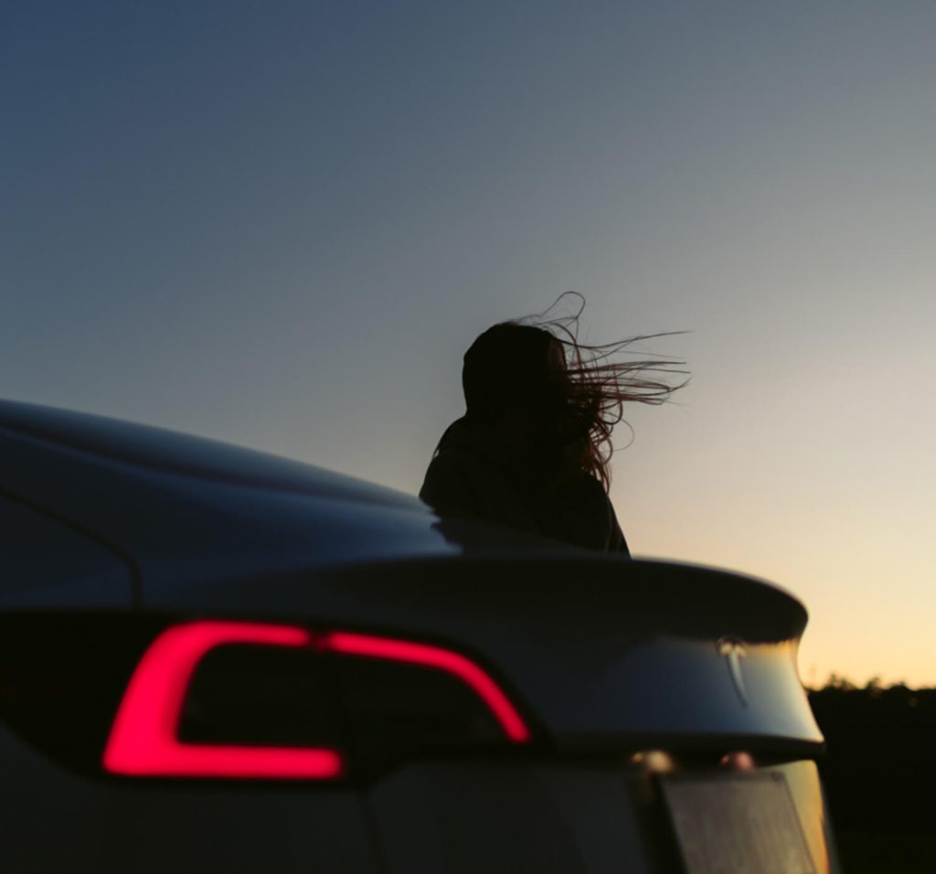 Silhouette of a person against the sunset sky next to an evee electric vehicle