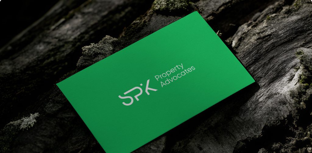 SPK Property Advocates business card resting on a dark textured rock surface